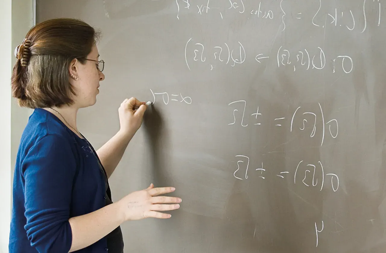 Student working on a math equation at a blackboard